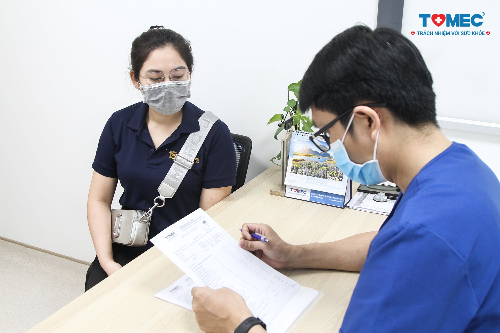bác sĩ khám và ghi hồ sơ cho khách hàng doanh nghiệp